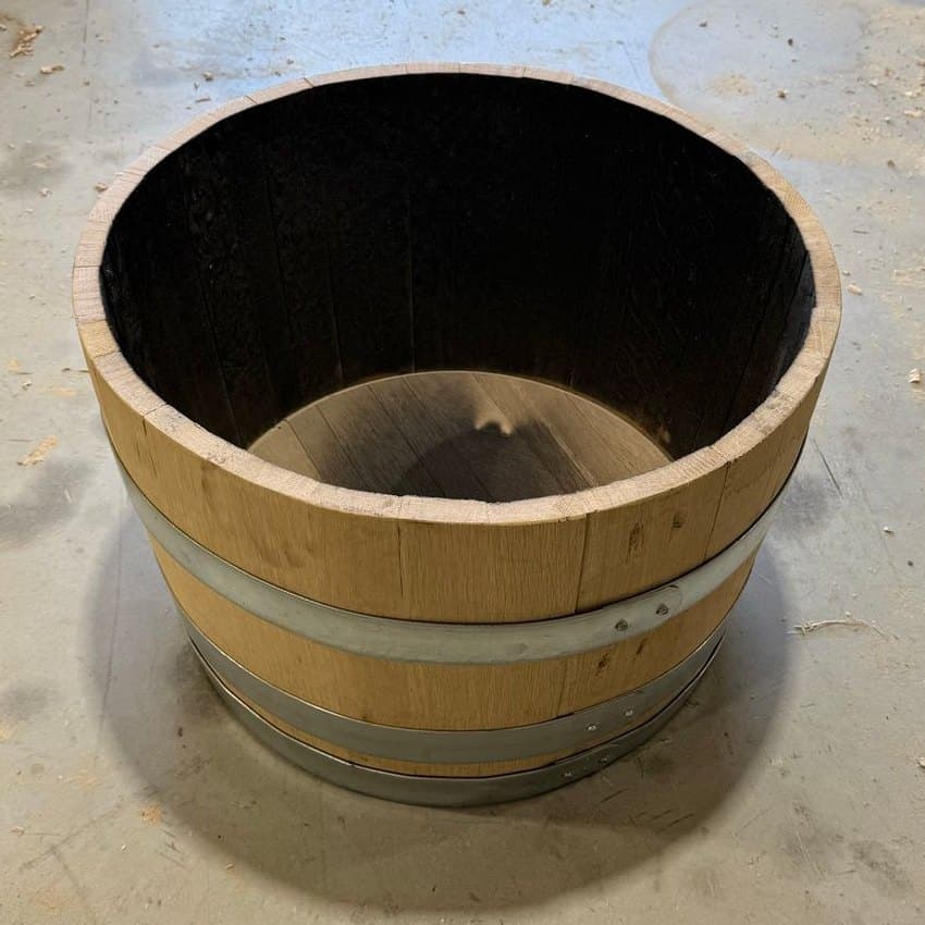 Freestanding oak half barrel with galvanized hoops and an open charred interior in the Standard Cooperage workshop