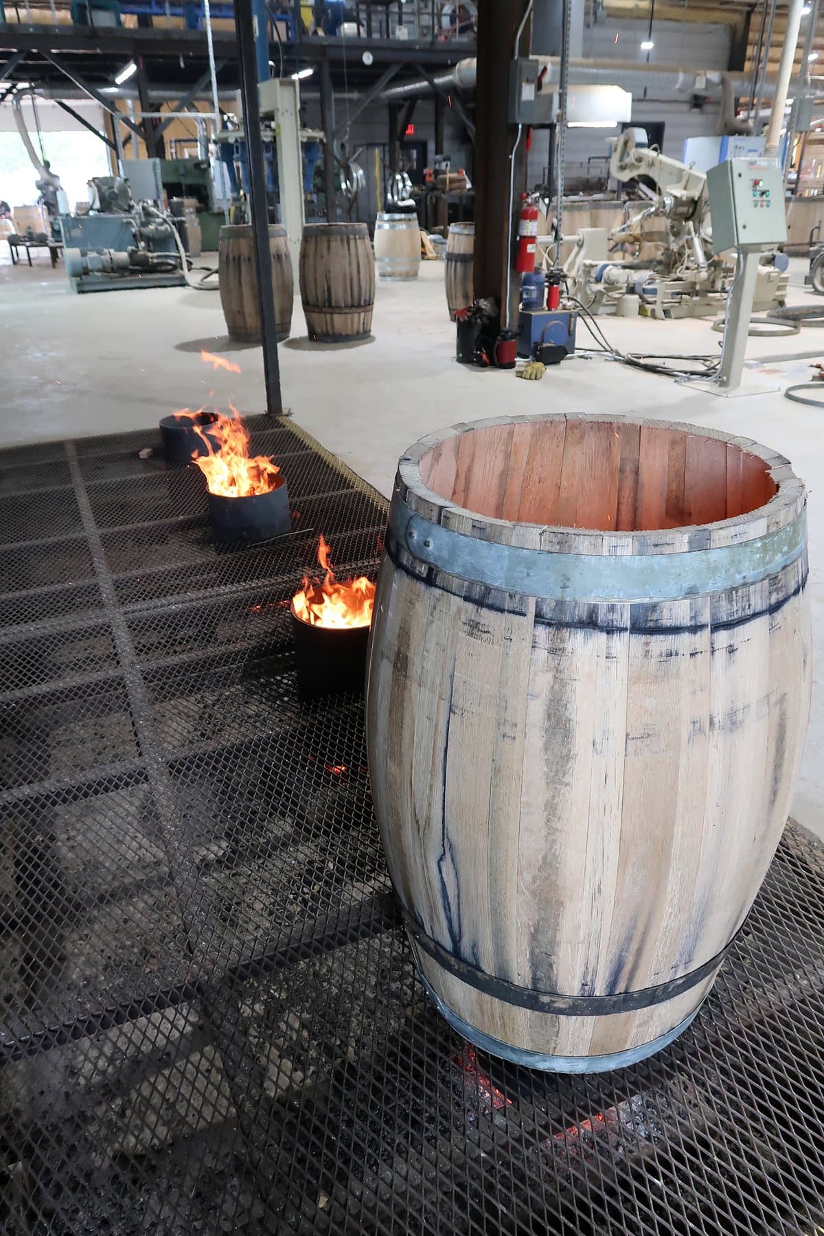 Raised oak barrel beside controlled fires at Standard Cooperage